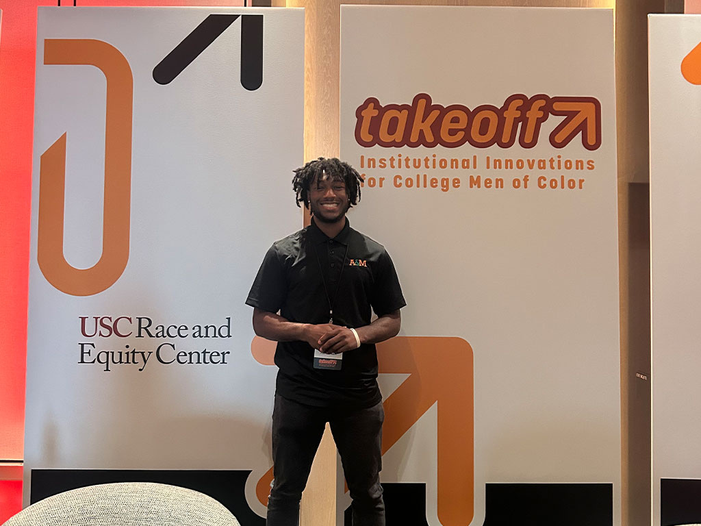 FAMU student poses infront of company sign during confernce. 