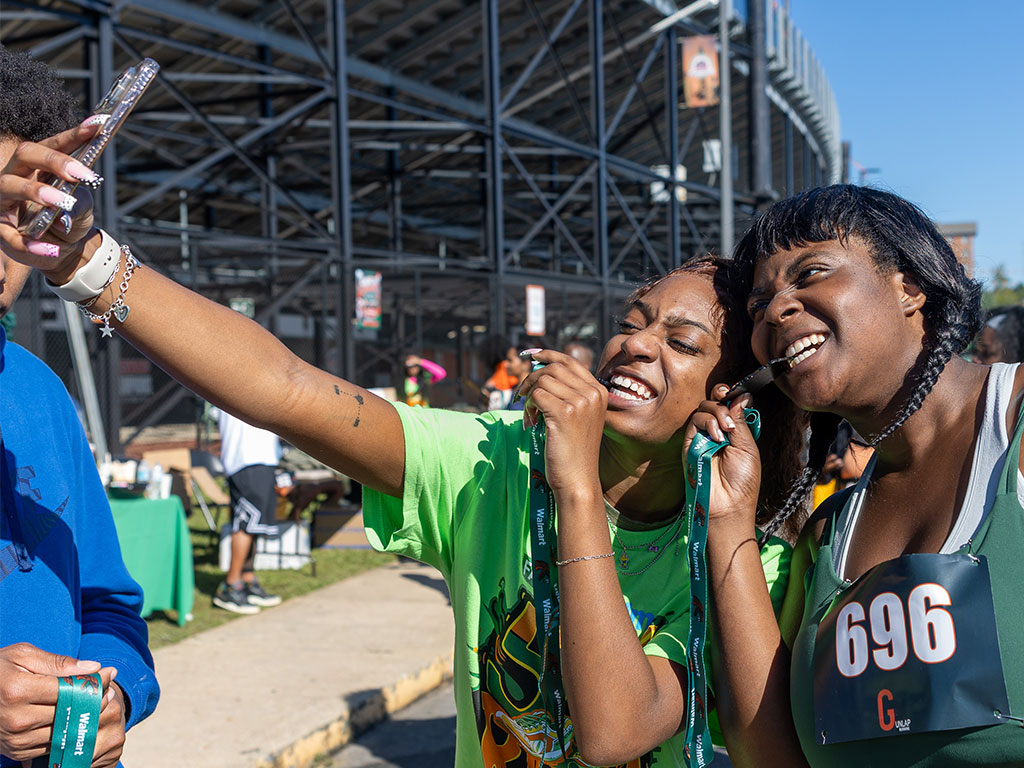 Two participants celebrate completing the fifth annual Walmart-sponsored FAMU Homecoming 5K Run/Walk by showing off their medals and posing for a selfie outside Bragg Memorial Stadium on Thursday, Oct. 22, 2026.  Photo courtesy of Jeff Adams.