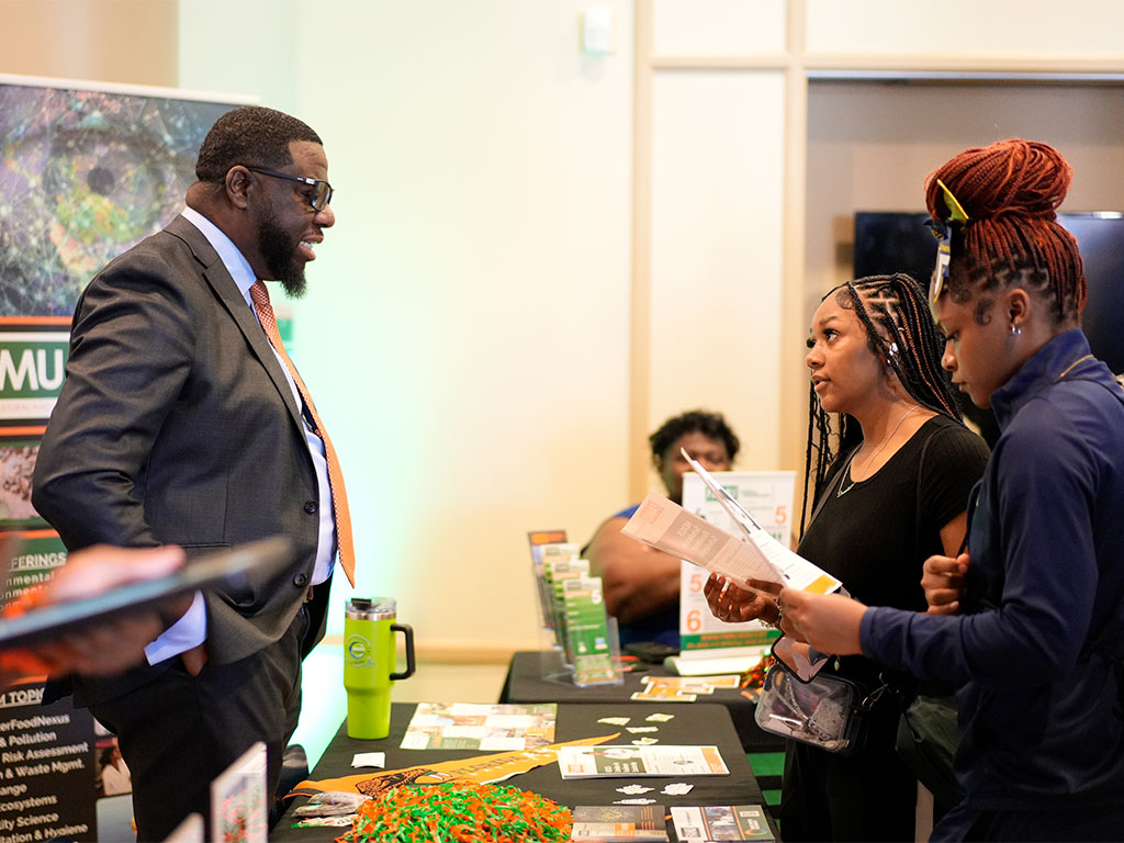 A FAMU representative discusses academic programs and enrollment opportunities with prospective students, providing information to help guide their college decisions.