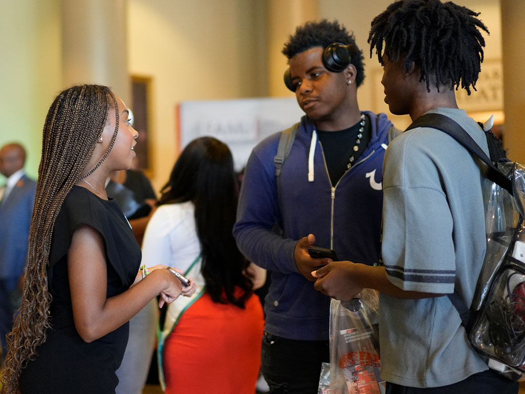 A Florida A&M University student representative speaks with prospective students during a recruitment event, sharing insights about campus life and opportunities available to future Rattlers.