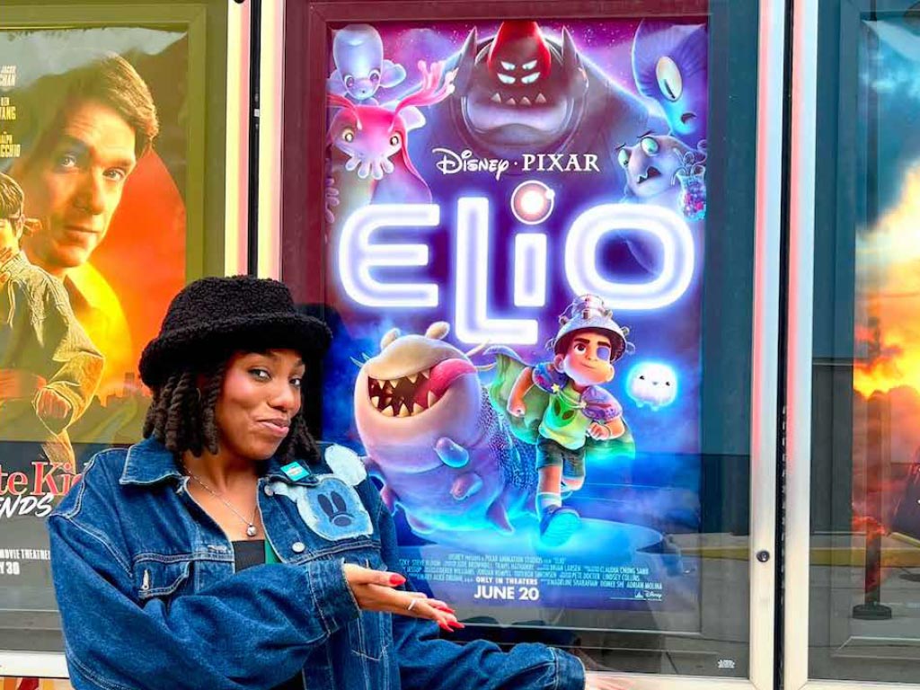 Brianna Grant stand in-front of an Elio movie poster