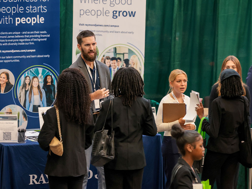 A recruiter engages with Florida A&M University students during a career fair, offering insights and opportunities as students present résumés and explore potential career paths.