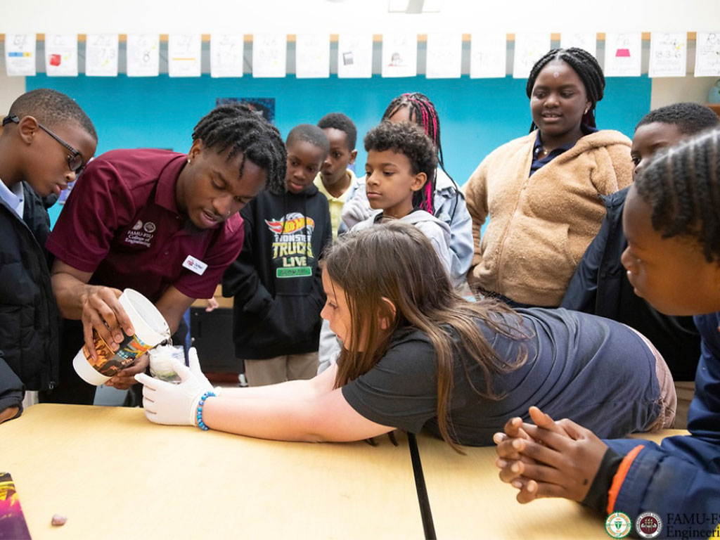 Da’Mari Clayton engages with local K-12 students during a hands-on engineering demonstration, showcasing his passion for mentorship and STEM education through the Engineering Ambassadors program.