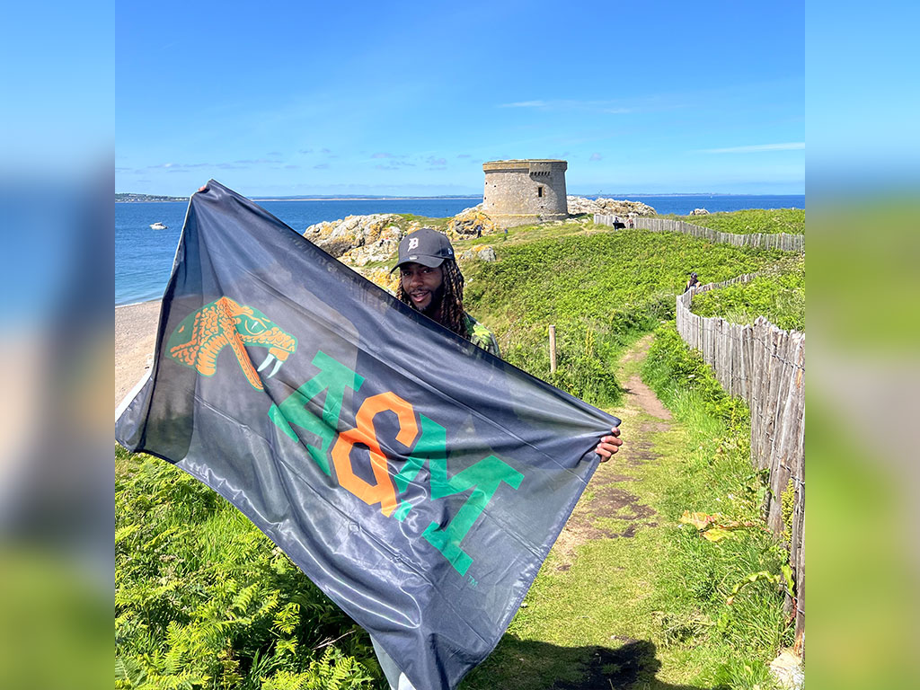 Florida A&M University senior Delvonz Flamand proudly displays the FAMU flag during his study abroad experience, representing Rattler pride while exploring a new culture and gaining international experience.