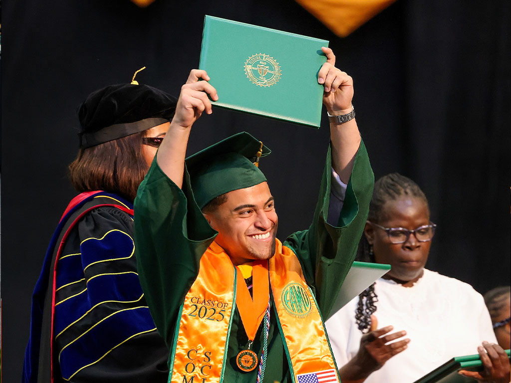 FAMU graduate holding his diploma in the air