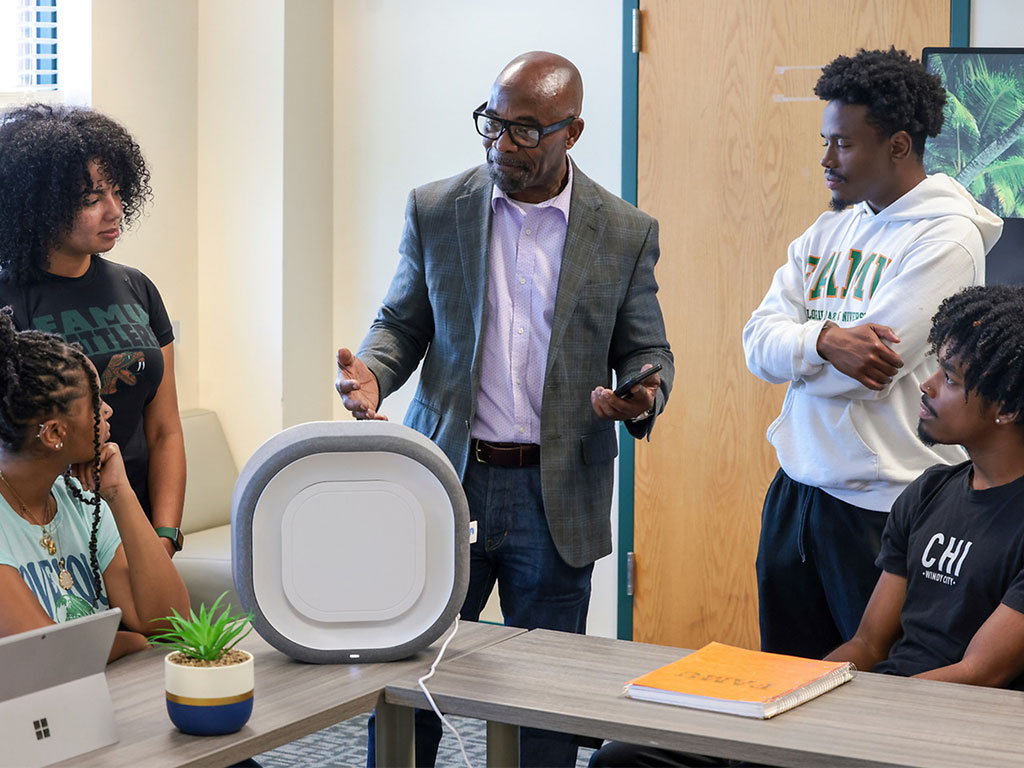 Victor Ibeanusi, Ph.D., dean of Florida A&M University's School of the Environment, discusses the capabilities of the Center of Excellence for Indoor Air Quality's environmental monitoring sensor with students. The technology collects real-time data that supports research in hurricane preparedness, climate resilience and public health while providing students with hands-on learning experiences. (Photo courtesy of Florida A&M University.)
