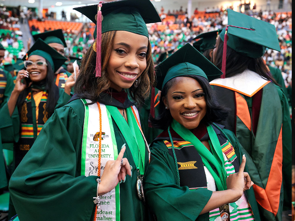 Two FAMU graduates throwing their AKA pinkies up symbol