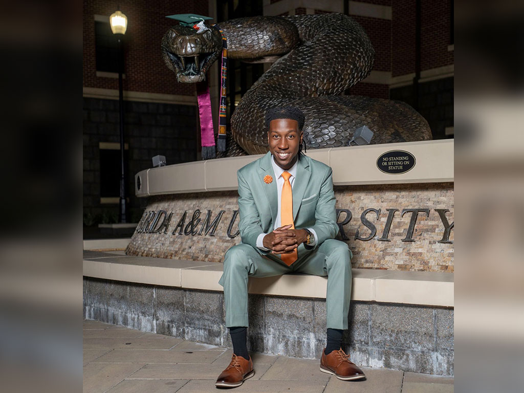Jayden “JB” Patterson celebrates his FAMU journey in front of the university’s iconic “The Rattler” statue.