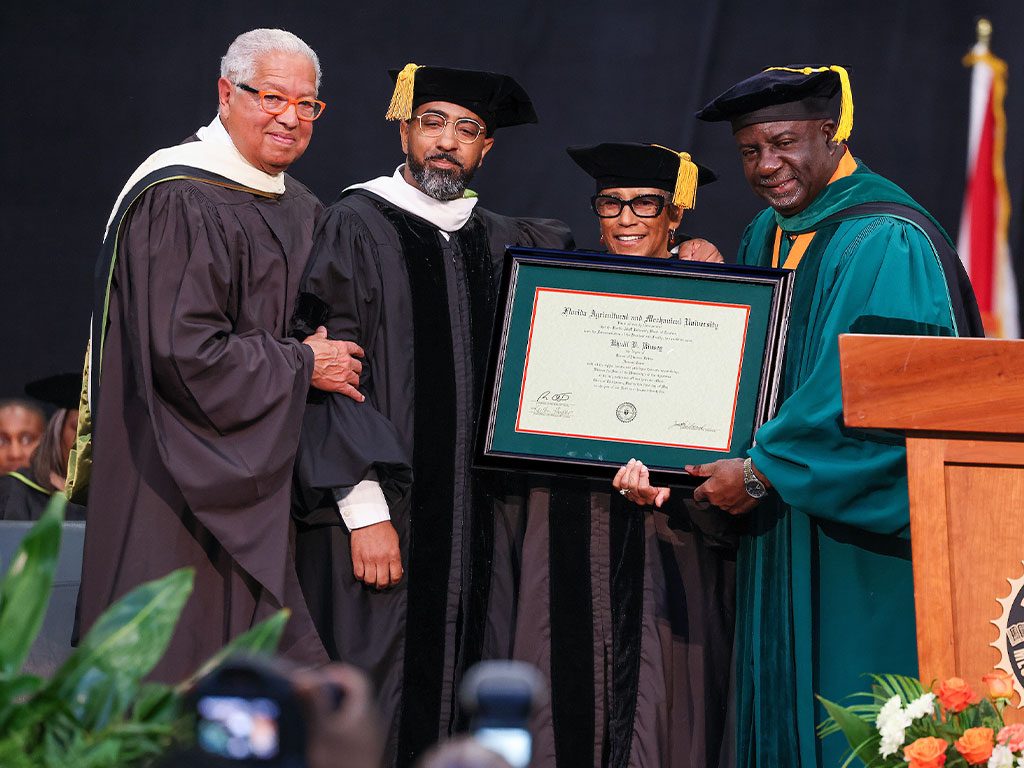 The Kinsey family members Khalil and mother, Shirley, receive honorary doctorates flanked by Bernard Kinsey and Interim President Beard