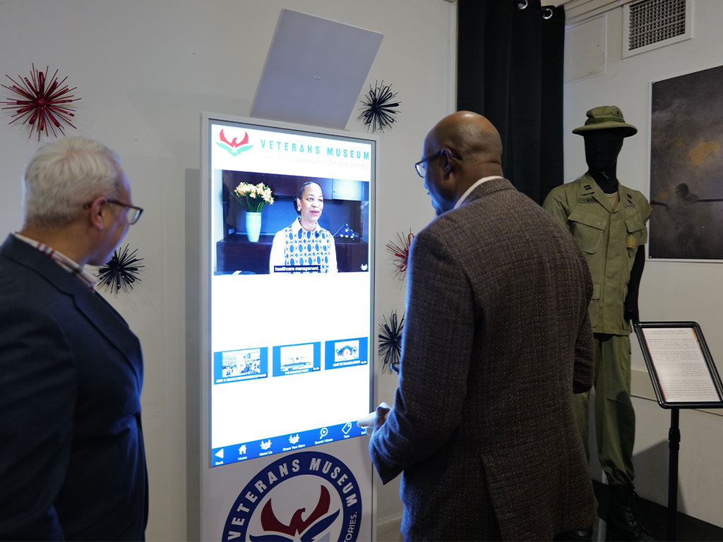 Visitors explore an interactive display at the Meek-Eaton Black Archives exhibit at Florida A&M University, engaging with digital stories and artifacts that bring African American military history to life.