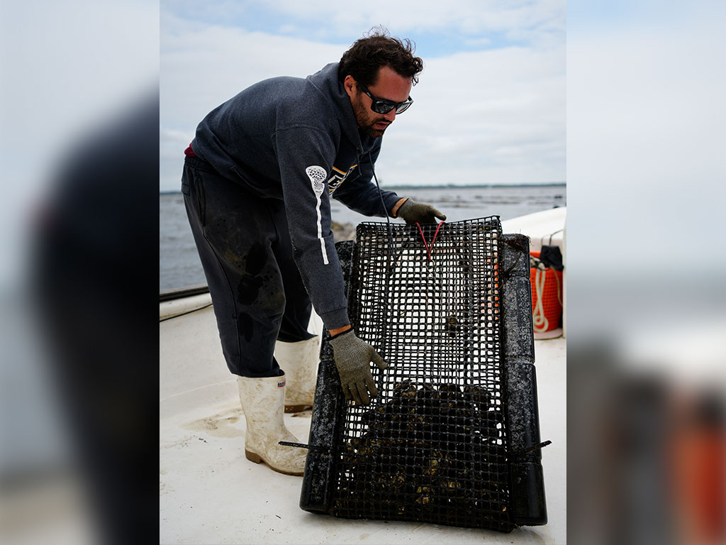 Chad Minter, owner of S&M Oyster Company, works aboard his oyster farm in Spring Creek. Real-time water quality data collected by FAMU's "Rattler Moji" buoy helps oyster farmers monitor environmental conditions that can affect production and oyster quality.