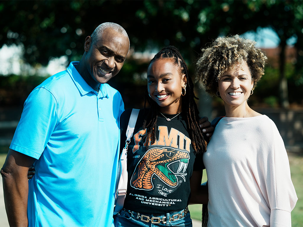 A prospective Florida A&M University student poses with family members while proudly representing the Rattler spirit, highlighting the role of family support and personal connections in the college recruitment experience.