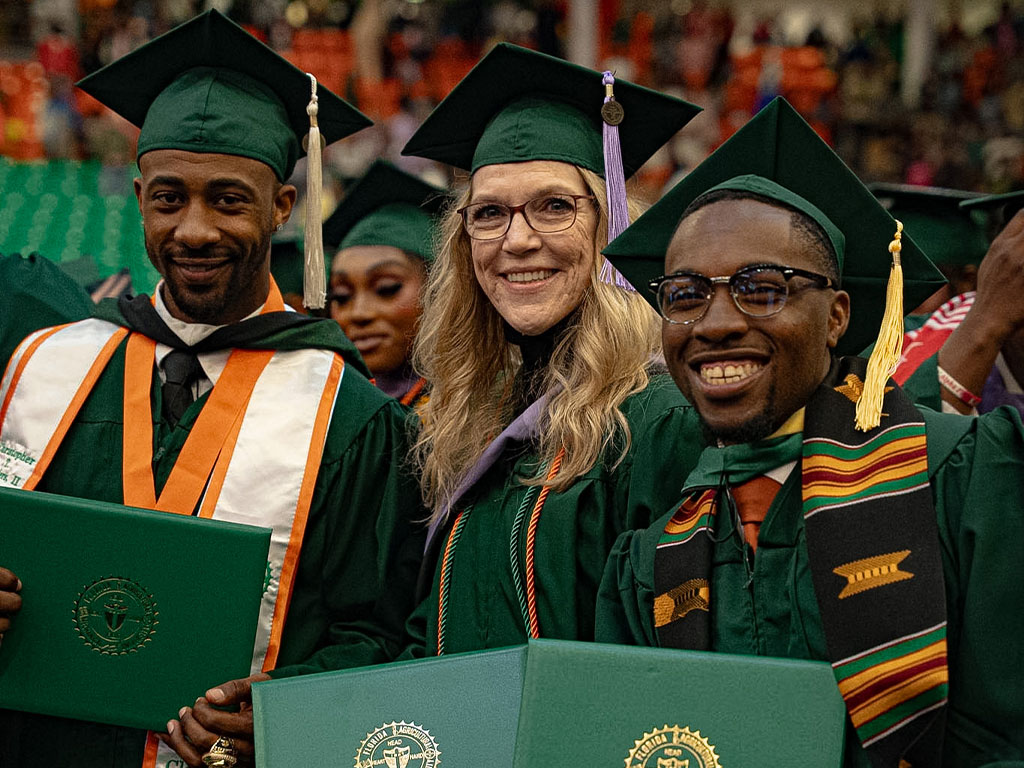 Graduates smiling in the crowd.