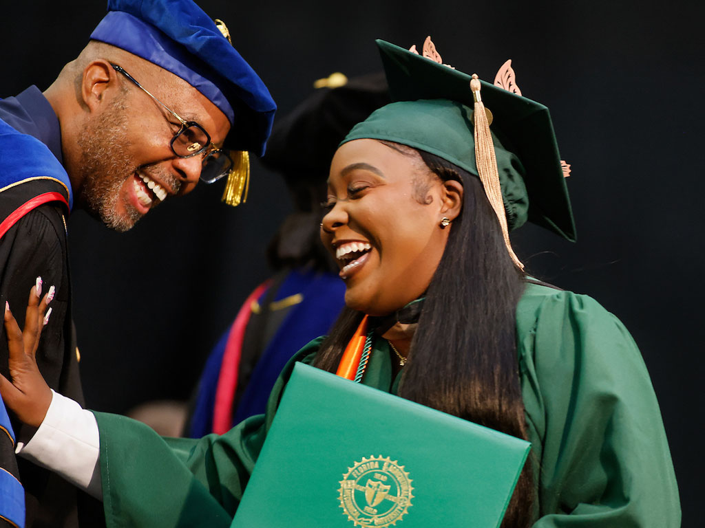 Graduate bursting with smiles and laughter accepting her degree.