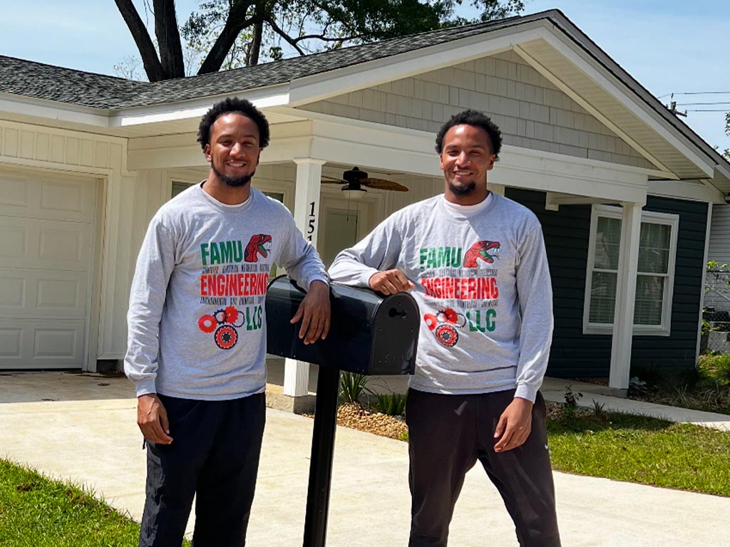 Twins pose infront of newly constructed house. 